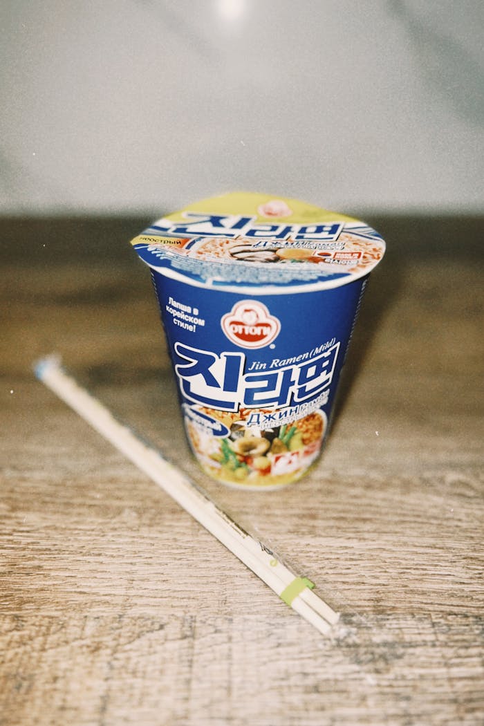 A cup of instant noodles with chopsticks on a wooden table, perfect for a quick meal.