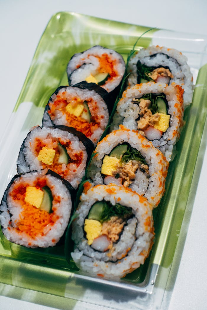 Close-up of fresh sushi rolls with diverse fillings in a plastic bento box, perfect for lunch or dinner.